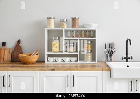 Vasetti con cereali, spezie e utensili da cucina Foto Stock