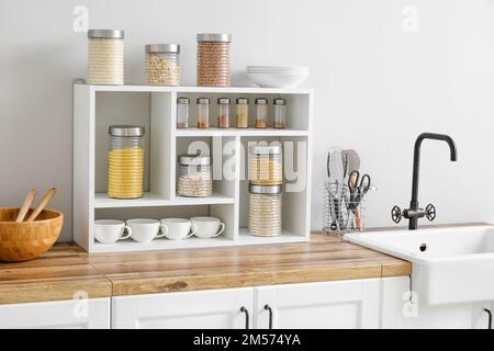 Vasetti con cereali, spezie e utensili da cucina Foto Stock