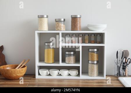 Vasetti con cereali, spezie e utensili da cucina Foto Stock