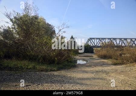 Percorso sterrato con pozze con un ponte sullo sfondo in campagna Foto Stock