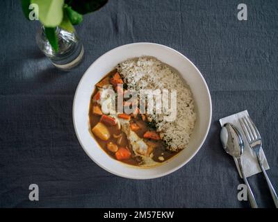 Portare con sé vegetariani e riso in un recipiente bianco al tavolo Foto Stock