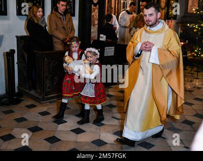 Cracovia, Polonia. 25th Dec, 2022. La figura di Gesù Bambino portata da due ragazze in costumi di Cracovia. La notte del 24/25 dicembre (dopo la vigilia di Natale) alle 12:00:00 presso la Cattedrale di Wawel a Cracovia, si tiene una messa di mezzanotte sotto la guida del Metropolita di Cracovia. Credit: SOPA Images Limited/Alamy Live News Foto Stock