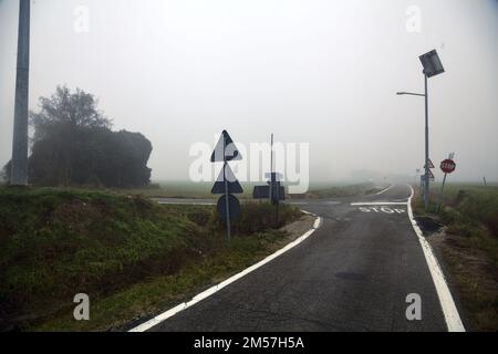 Crocevia accanto ad una casa abbandonata in una giornata di nebbia nella campagna italiana Foto Stock