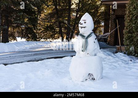Pupazzo di neve naturale con una sciarpa in strada della città nordamericana Foto Stock
