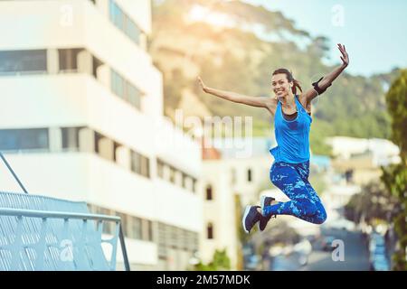 Essere vittoriosi. una giovane donna che salta a mezz'aria dopo il suo allenamento. Foto Stock