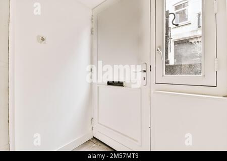 l'interno di una stanza con pareti bianche e pavimenti in legno, compresa una porta che conduce ad una piccola finestra Foto Stock