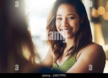 Ricordati sempre di sorridere. una donna che chiacchiera con la sua amica in un bar. Foto Stock