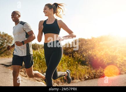 Si mantengono in azione. una giovane coppia in forma che va per una corsa all'aperto. Foto Stock