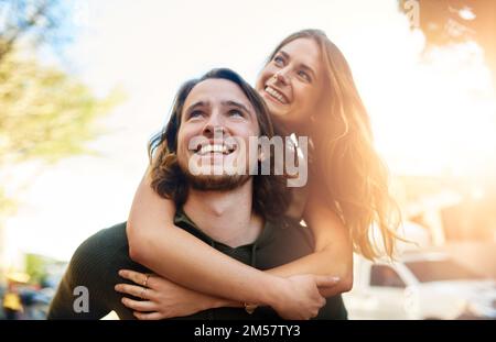 Innamorato. una giovane coppia felice che si gode un giro di piggyback all'aperto. Foto Stock