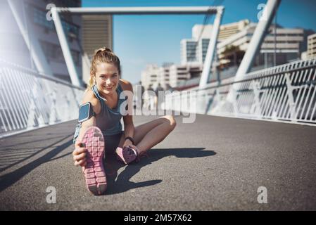 Stretching quei muscoli prima di colpire la strada. Ritratto di una giovane donna sportiva che si allunga prima di una corsa. Foto Stock