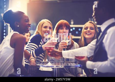 Tenete che quelle bevande vengano, cameriere. un cocktail cameriere che serve drink a un gruppo di amici in un night club. Foto Stock