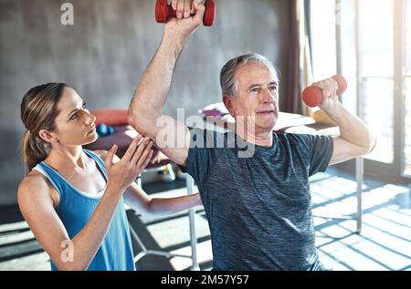 Continua a essere forte. un uomo anziano che lavora con il suo fisioterapista. Foto Stock