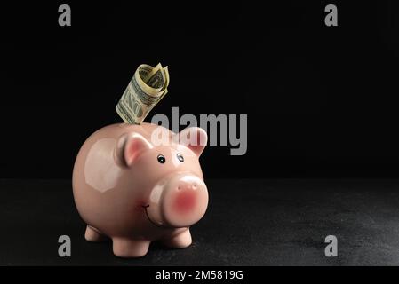 Piggy bank con dollari su sfondo nero, spazio vuoto per il testo. Cattive notizie nel mercato finanziario Foto Stock