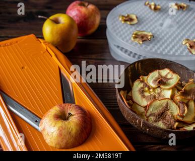 Il processo di produzione di mele essiccate con mele fresche e attrezzi su tavola di legno Foto Stock