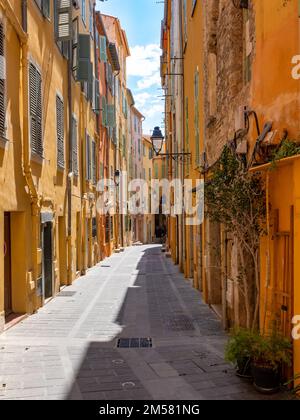 Una strada dritta colorata della vecchia Mentone, Francia senza persone. Preso in un giorno di primavera di sole. Foto Stock