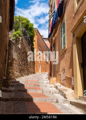 Una strada tortuosa e colorata della vecchia Mentone, Francia senza persone. Preso in un giorno di primavera di sole. Foto Stock