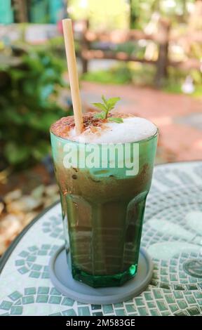 Latte di cacao in menta ghiacciata servito sul tavolo da tè in giardino Foto Stock