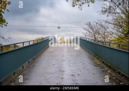 Un ripido ponte pedonale conduce verso il cielo con una luce sospesa sul filo Foto Stock