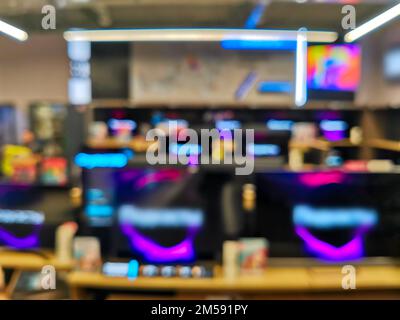 Vetrina con i televisori nel moderno negozio di elettronica. Acquista un TV. Molti TV sullo scaffale del negozio di tecnologia. Immagine sfocata come sfondo. Foto Stock