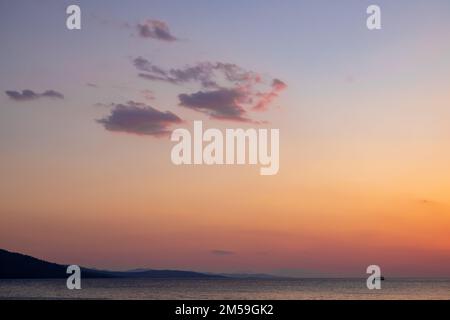 le nuvole appaiono quando il cielo cambia da blu a rosso al tramonto Foto Stock