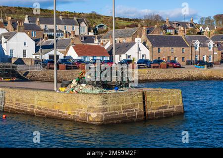 Muro del porto e edifici sul lungomare nel villaggio costiero di Johnshaven sulla costa del Mare del Nord dell'Aberdeenshire in Scozia, Regno Unito Foto Stock