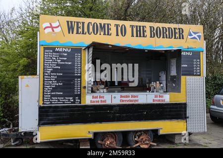 Cafe,burger van,Road,food,outlet,at,border crossing,next,to,big,big,massive,Welcome to Scotland,Failte GU Alba,flag,also known as, salitire, dates back to the 12th Century,signage,signpost,at,border,between Scotland and leaving England,flag,also chiamato, Saint Andrew's Cross, or the, crux decussata, is a diagonal symbol in the cross. Foto Stock