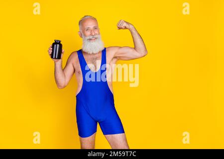 Foto di carino sportivo uomo pensionato vestito blu generale crescente sport polvere vaso mostrando bicipiti spazio vuoto isolato giallo sfondo Foto Stock