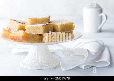 Barrette di limone impilate su un supporto dessert con zucchero a velo dietro. Foto Stock