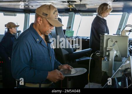 MARE DELLE FILIPPINE (13 FEBBRAIO 2022) STATI UNITI Blu marino Lt. CMdR. Valon Walker, assistente per il controllo dei danni della portaerei di classe Nimitz USS Abraham Lincoln (CVN 72), verifica il percorso della nave durante le operazioni di volo a sostegno dell'esercizio di Jungle Warfare 22 (JWX 22) in Okinawa, Giappone, 13 febbraio 2022. JWX 22 è un'esercitazione di formazione sul campo su larga scala incentrata sull'utilizzo delle capacità integrate di partner congiunti e alleati per rafforzare la consapevolezza, la manovra e gli incendi in tutti i settori in un ambiente marittimo distribuito. Foto Stock