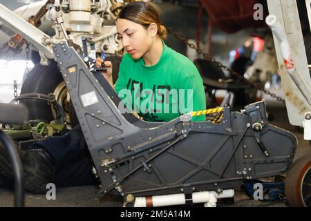 PHILIPPINE SEA (13 febbraio 2022) Aviation Structural Mechanic (Equipment) Airman Apprentice Janely Estrada, di Las Vegas, assegnato ai “Vigilantes” di Strike Fighter Squadron (VFA) 151, dipinge la sede di espulsione di un F/A-18E Super Hornet nella baia hangar a bordo della portaerei di classe Nimitz USS Abraham Lincoln (CVN 72). Abraham Lincoln Strike Group è in fase di implementazione pianificata nell'area delle operazioni della flotta 7th degli Stati Uniti per migliorare l'interoperabilità attraverso alleanze e partnership e al tempo stesso fungere da forza di risposta pronta a sostegno di una regione indomPacifico libera e aperta. Foto Stock