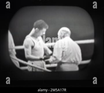 Fine del 1950s, storico, un televisore dell'epoca che mostra una partita di boxe, l'arbitro parlando con un pugile nel suo angolo. Molto probabilmente un clip da Sportsview, un programma di sport di metà settimana di BBC Television, presentato da Peter Dimmock, che è stato trasmesso dal 1954 al 1968. Foto Stock