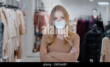 Successo bionda giovane donna venditore consulente ragazza negozio di abbigliamento proprietario piccola impresa donna acquirente cliente cliente in maschera medica in piedi in centro commerciale Foto Stock