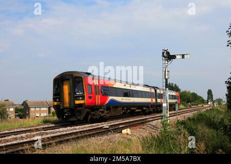 East Midlands Railway Regional train 158 857 passando un segnale Semaphore, Whittlesey città, Fenland, Cambridgeshire, Inghilterra Foto Stock