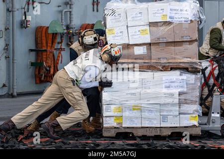 MARE DELLE FILIPPINE (15 febbraio 2022) Gunnery Sgt. Anthony Curtis, di Miami, assegnato alla nave d'assalto anfibio USS America (LHA 6), sposta i negozi sul ponte di volo durante un rifornimento verticale con l'oliatore di rifornimento della flotta USNS Yukon (T-AO 202). L'America, nave guida dell'America Amphibious Ready Group, insieme alla Marine Expeditionary Unit 31st, opera nell'area di responsabilità della flotta statunitense 7th per migliorare l'interoperabilità con alleati e partner e fungere da pronta forza di risposta per difendere la pace e la stabilità nella regione dell'Indo-Pacifico. Foto Stock