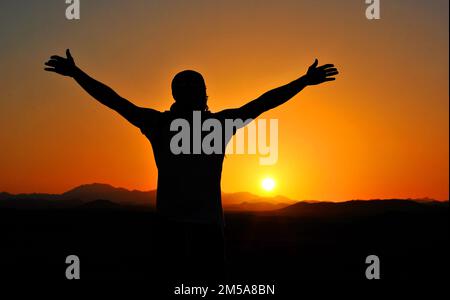 Tramonto con la silhouette di un uomo. Tramonto sullo sfondo. Colori dorati e arancioni. Tramonto di Fiery in Egitto. Foto Stock