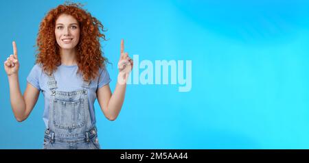 Motivata allegra redhead sciocca ricci donna che punta su inrdex dito sorridente affascinato impressionato eccitato mostrando impressionante promo discutere Foto Stock