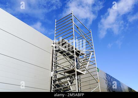 Moderna impalcatura tubolare di metallo multilivello accanto alla facciata a pannelli sandwich di un nuovo edificio Foto Stock