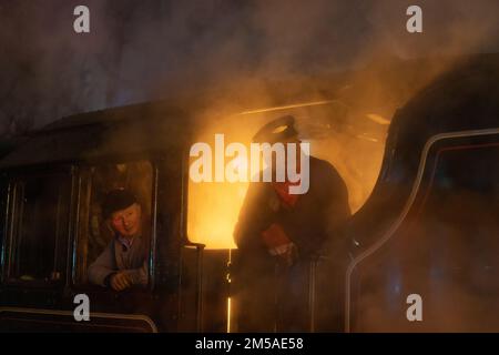 Allenatore di una locomotiva a vapore che guarda fuori dalla cabina su una nuvola di vapore Foto Stock