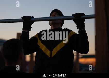 NEGLI STATI UNITI Militare Soldato, assegnato a 4th Divisione di Fanteria Artillery (DIVARTY), esegue un chin-up durante la sfida DIVARTY Ivy Gunners Howitzer M777, 16 febbraio 2022, a Pershing Field, Fort Carson, Colorado. Squadre di quattro hanno completato sette ripetizioni di vari esercizi a corpo intero. Foto Stock