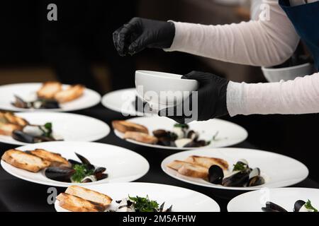 capo che serve cozze in salsa di vino bianco e pane bianco toast Foto Stock