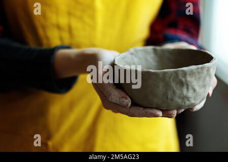 Ceramica donna in grembiule di formatura creta Bowl.Hands di ceramista professionale creare stoviglie di ceramica sul posto di lavoro. Hobby.piccola impresa artigianale con Foto Stock