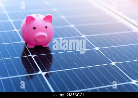 Concetto di risparmio energetico con pannelli solari e un banco di porcellini Foto Stock