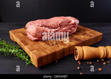 Bistecca di manzo cruda fresca sul tagliere di legno, vista dall'alto. Servito su sfondo nero. Banner Web design con spazio di copia. Cibo fresco biologico sano Foto Stock