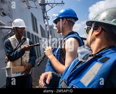 MAR DELLA CINA DEL SUD (16 febbraio 2022) Ospedale Corpsman Tyler Samuel-Smith, da Charlotte, N.C., istruisce i marinai a bordo di Arleigh Burke-classe cacciatorpediniere missilistico guidato USS Ralph Johnson (DDG 114) per applicare la protezione solare prima di un rifornimento in mare con la nave a secco di Lewis e Clark USNS Amelia Earhart (T-AKE-6). Ralph Johnson è assegnato alla Task Force 71/Destroyer Squadron (DESRON) 15, la più grande DESRON della Marina e la principale forza di superficie della flotta statunitense 7th. Foto Stock