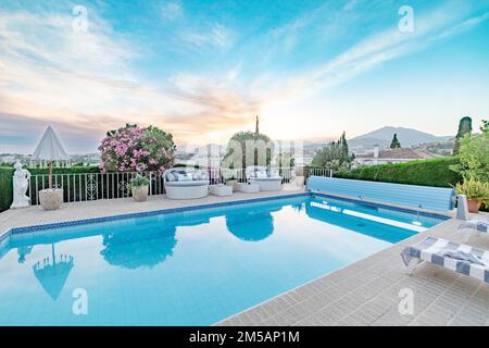 Un giardino pieno di sedie a sdraio e una piscina lungo la Costa del Sol primo piano Foto Stock