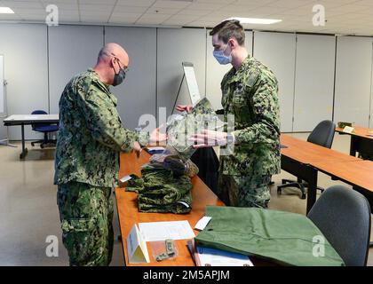 FORT WORTH, Texas (16 febbraio 2022) - Navy Reserve Region Readiness and Mobilization Command Fort Worth Adaptive Mobilitation Department staff member Logistics Specialist 1st Class Wilfred Graf, left, rilascia articoli uniformi all'ospedale Corpsman 3rd Class Garrett Beaudry, assegnato alla Naval Branch Health Clinic San Diego, In preparazione all’incarico individuale di augmentee (IA) di Beaudry a Guantamo Bay, Cuba. La IA e la mobilitazione per la lavorazione delle riserve selezionate per Beaudry e altri marinai hanno avuto luogo durante un evento di abilitazione alla mobilizzazione adattiva presso la Navy Reserve Region Readiness and Mobilization COM Foto Stock