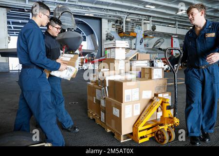 MARE DELLE FILIPPINE (17 febbraio 2022) i marinai organizzano il carico nella baia dell'hangar a bordo della portaerei di classe Nimitz USS Abraham Lincoln (CVN 72). Abraham Lincoln Strike Group è in fase di implementazione pianificata nell'area delle operazioni della flotta 7th degli Stati Uniti per migliorare l'interoperabilità attraverso alleanze e partnership e al tempo stesso fungere da forza di risposta pronta a sostegno di una regione indomPacifico libera e aperta. Foto Stock