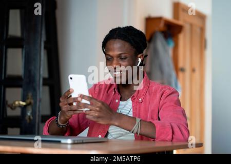 Allegro ottimista afroamericano che effettua la videochiamata agli amici che fanno il lavoro freelance in tempo Foto Stock