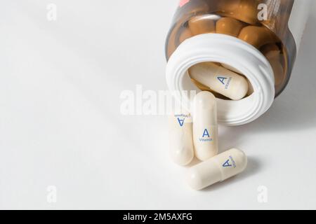 Vitamina A. vitamine in capsule per la salute di denti, ossa, mucose e pelle. Le capsule bianche con vitamina A o retinolo sono sparse sopra Foto Stock