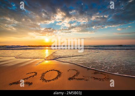 Buon anno 2023 testo sulla spiaggia di sabbia durante la mattina panoramica. Alba sulla riva del mare. Foto Stock